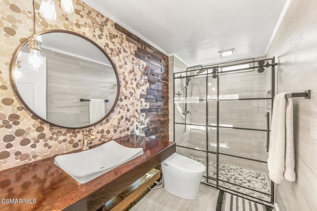 bathroom featuring sink, toilet, ornamental molding, tile walls, and a shower with shower door