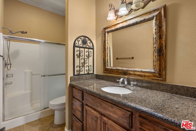 bathroom featuring tile patterned flooring, crown molding, toilet, vanity, and a shower with shower door