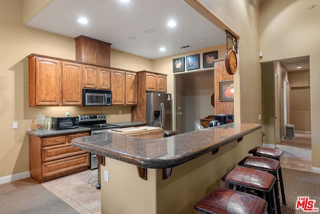 kitchen featuring light colored carpet, kitchen peninsula, stainless steel appliances, and a breakfast bar area