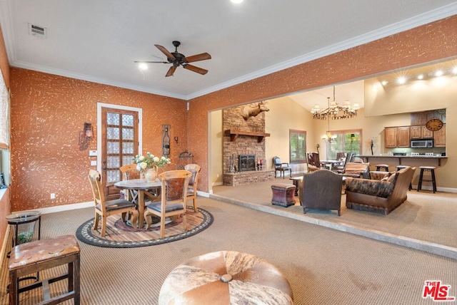 carpeted living room featuring lofted ceiling, a stone fireplace, ornamental molding, and ceiling fan with notable chandelier