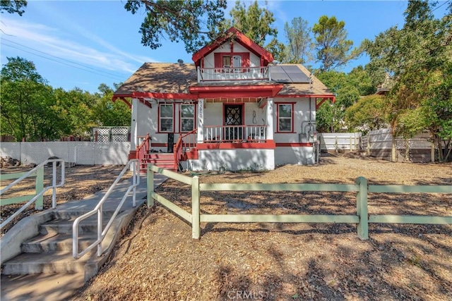 view of front of house featuring a porch, a fenced front yard, and solar panels