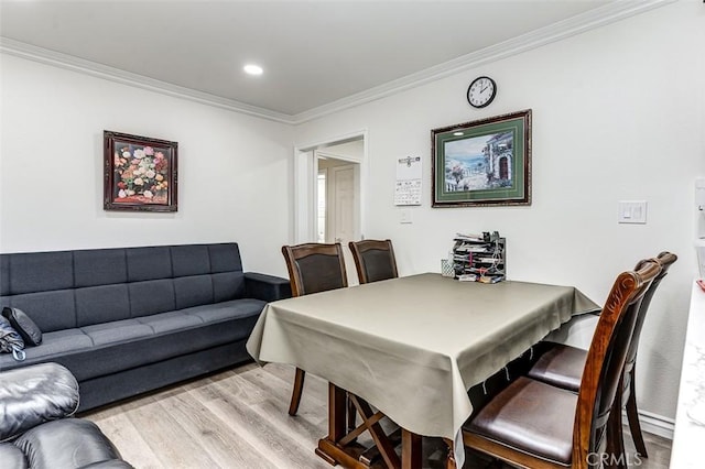 dining area with light hardwood / wood-style floors and ornamental molding