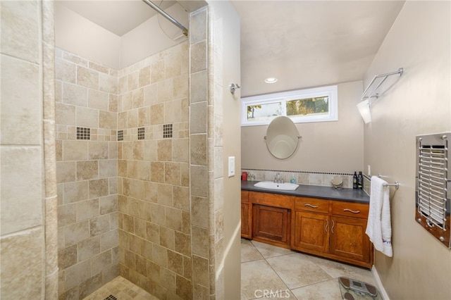 bathroom with tile patterned flooring, a tile shower, and vanity