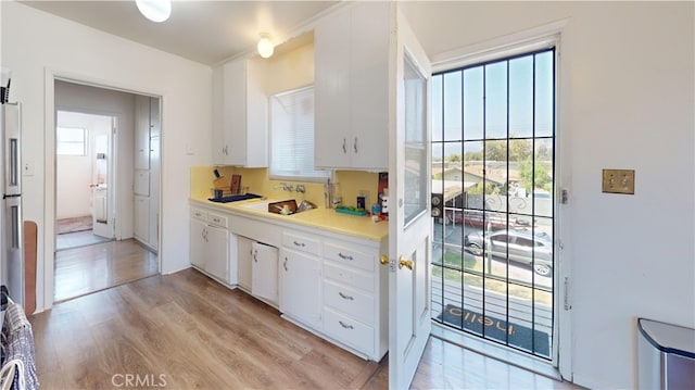 kitchen with stainless steel fridge, sink, white cabinets, and light hardwood / wood-style flooring