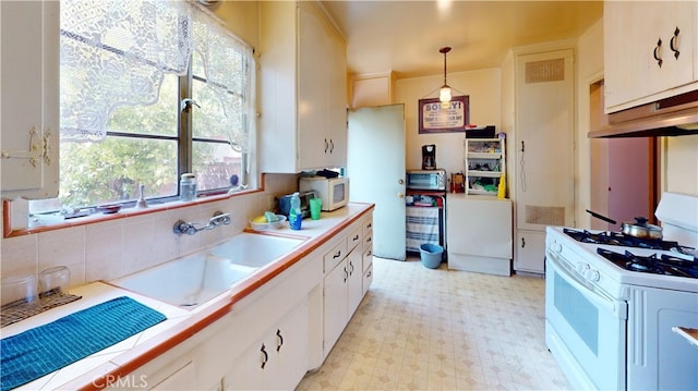 kitchen with backsplash, white appliances, pendant lighting, white cabinetry, and tile counters