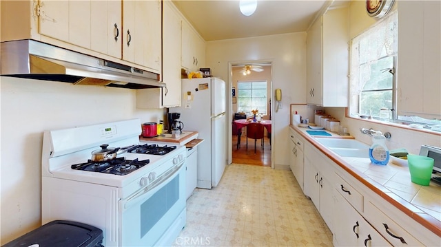 kitchen with white cabinets, white appliances, tile counters, and sink