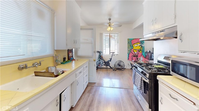 kitchen with appliances with stainless steel finishes, ceiling fan, sink, light hardwood / wood-style flooring, and white cabinetry