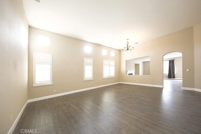 empty room featuring a notable chandelier and dark hardwood / wood-style flooring