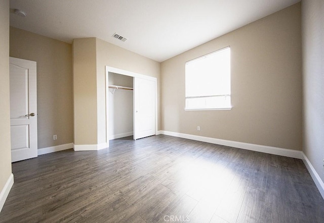 unfurnished bedroom featuring dark hardwood / wood-style floors and a closet