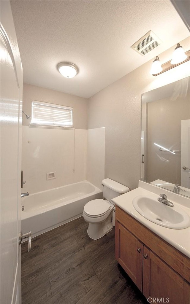 full bathroom featuring wood-type flooring, a textured ceiling, toilet, vanity, and shower / bathtub combination