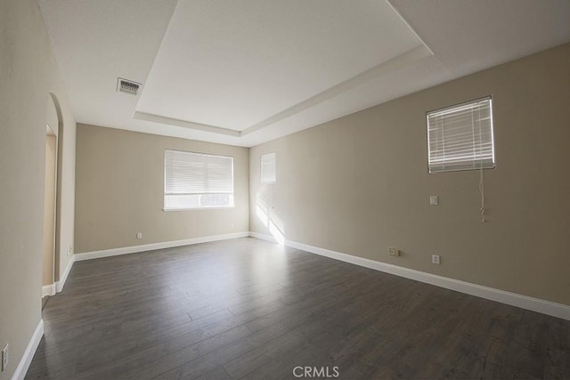 unfurnished room featuring a tray ceiling and dark wood-type flooring