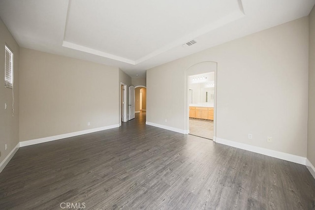 empty room featuring dark hardwood / wood-style flooring and a tray ceiling