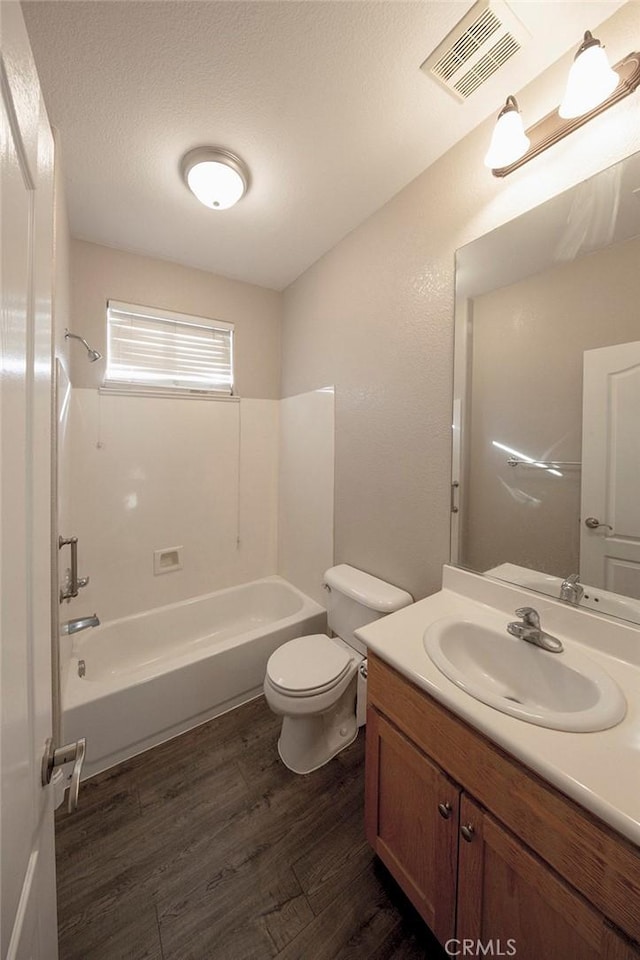 full bathroom with vanity, shower / tub combination, toilet, a textured ceiling, and wood-type flooring