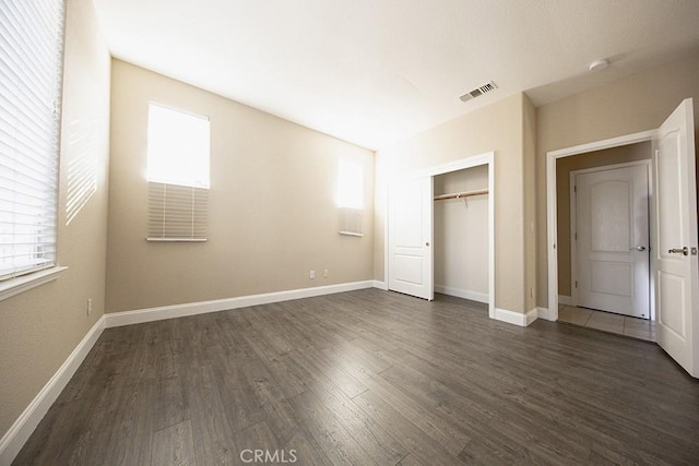 unfurnished bedroom with dark hardwood / wood-style floors and a closet