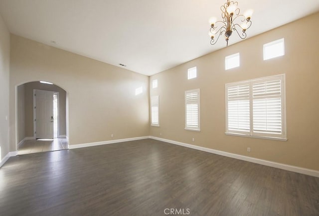 spare room with dark hardwood / wood-style floors, a wealth of natural light, and a notable chandelier