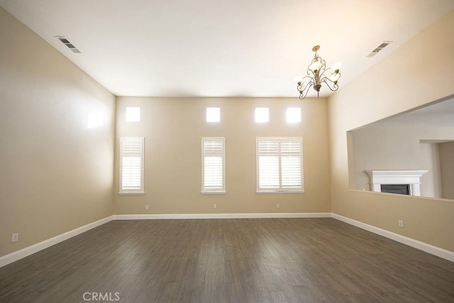 unfurnished room with plenty of natural light, dark wood-type flooring, and a notable chandelier