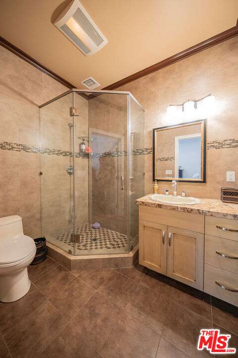 bathroom with a shower with door, toilet, vanity, and lofted ceiling