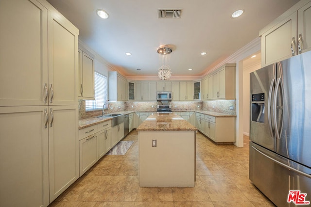 kitchen with appliances with stainless steel finishes, backsplash, decorative light fixtures, light stone countertops, and a kitchen island