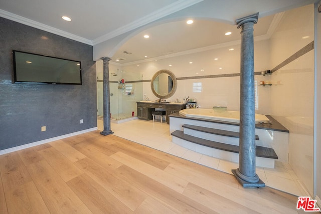 bathroom featuring decorative columns, hardwood / wood-style floors, a tub, and ornamental molding