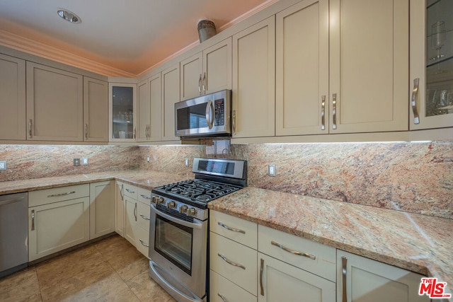 kitchen with light stone countertops, decorative backsplash, and appliances with stainless steel finishes