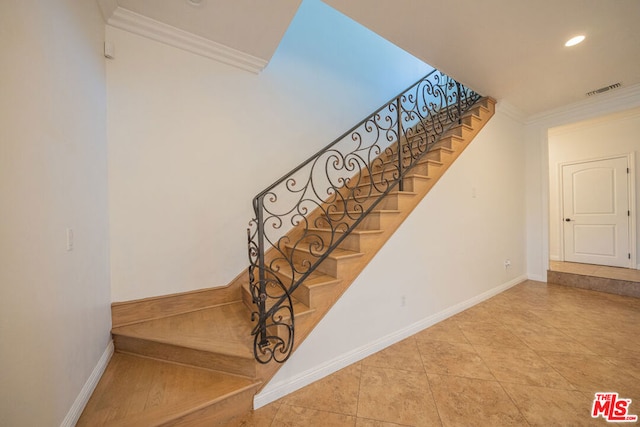 stairway with tile patterned floors and ornamental molding