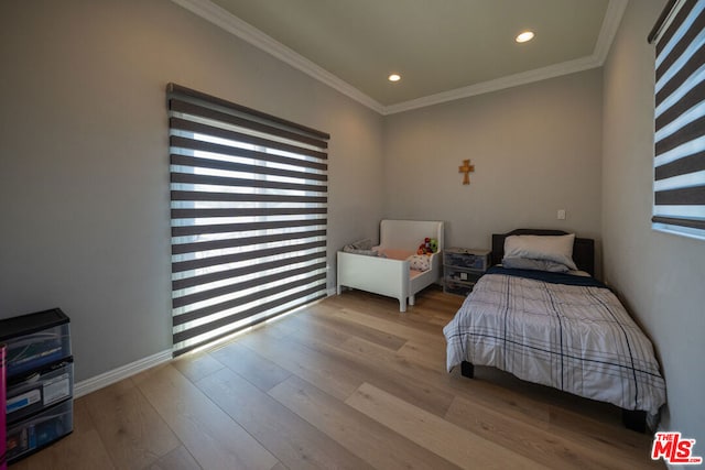 bedroom with crown molding and light hardwood / wood-style floors