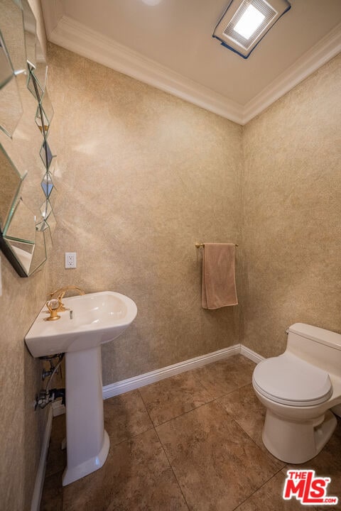 bathroom with toilet, tile patterned flooring, crown molding, and sink