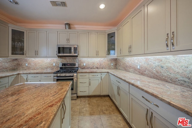 kitchen featuring tasteful backsplash, light stone countertops, light tile patterned flooring, and stainless steel appliances