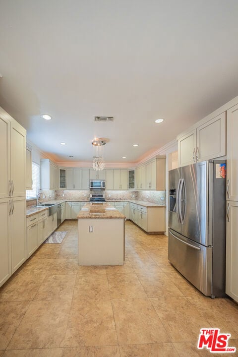 kitchen featuring sink, backsplash, appliances with stainless steel finishes, and a kitchen island