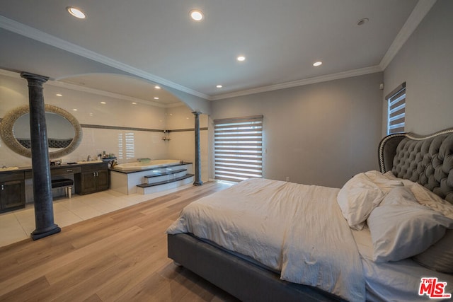 bedroom with crown molding, ornate columns, and light hardwood / wood-style flooring