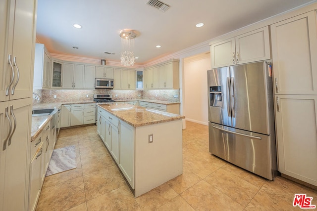 kitchen with pendant lighting, a kitchen island, decorative backsplash, light stone countertops, and stainless steel appliances