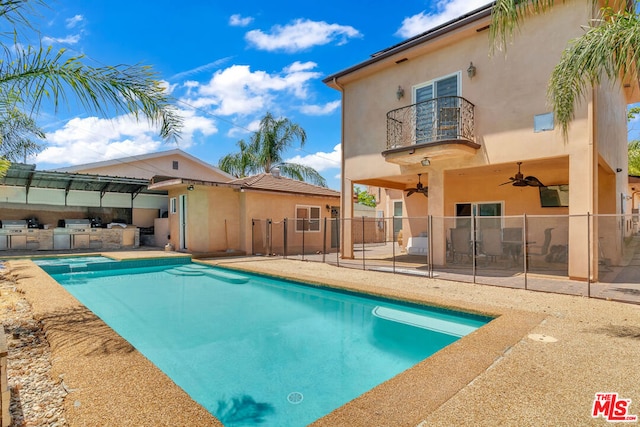 view of swimming pool featuring ceiling fan, a patio area, and an outdoor kitchen