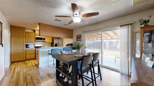 dining area with a textured ceiling, light hardwood / wood-style floors, and ceiling fan