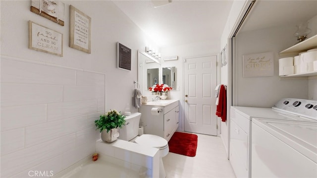 bathroom with vanity, separate washer and dryer, toilet, and a bathing tub