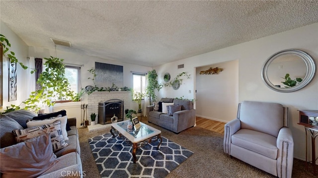 living room with carpet flooring, a textured ceiling, and a brick fireplace