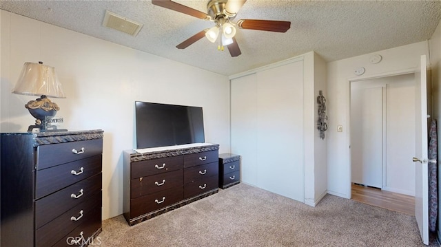 bedroom with ceiling fan, light carpet, and a textured ceiling