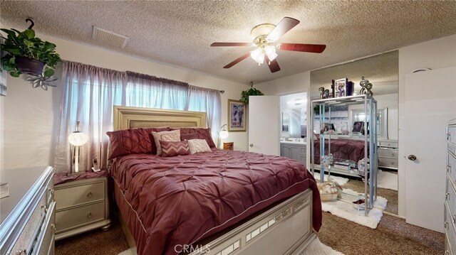 carpeted bedroom featuring a textured ceiling, ensuite bath, and ceiling fan