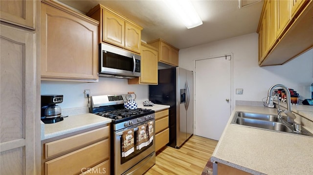 kitchen featuring sink, light hardwood / wood-style floors, light brown cabinets, and appliances with stainless steel finishes