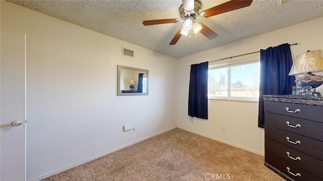 carpeted bedroom featuring ceiling fan and a textured ceiling