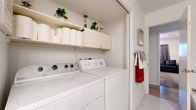 laundry room with independent washer and dryer, cabinets, and light wood-type flooring