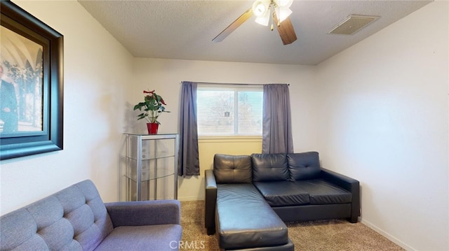 carpeted living room with ceiling fan and a textured ceiling