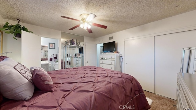 carpeted bedroom with a textured ceiling, ensuite bathroom, and ceiling fan