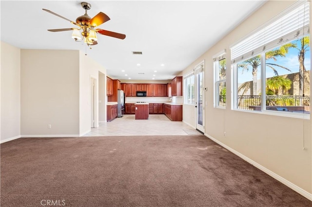 unfurnished living room featuring light colored carpet and ceiling fan