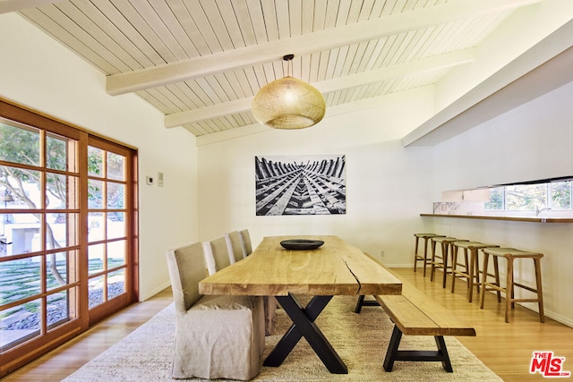 dining space featuring vaulted ceiling with beams, light hardwood / wood-style flooring, and wood ceiling