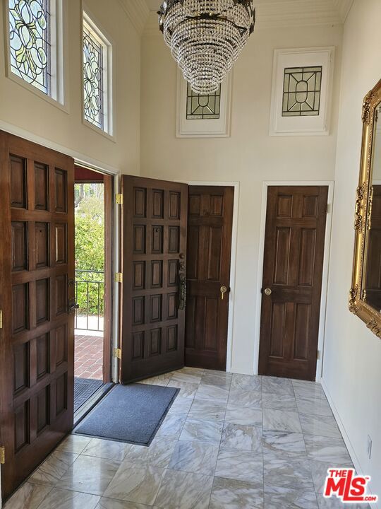 foyer with crown molding, a chandelier, and a high ceiling