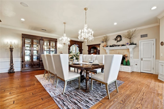 dining room with crown molding, light hardwood / wood-style flooring, and an inviting chandelier