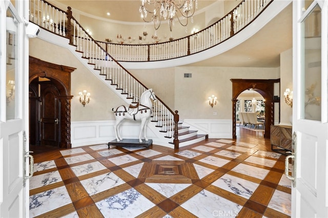 entryway featuring a high ceiling, ornamental molding, and a notable chandelier