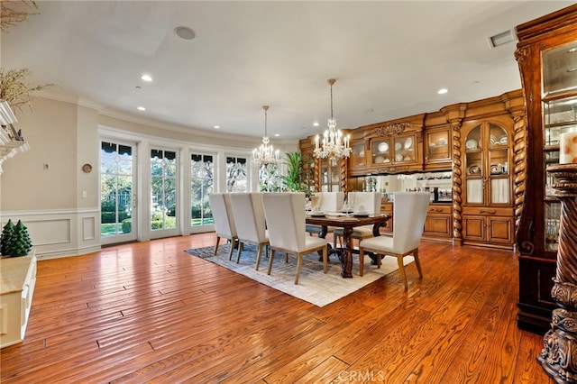 dining area with hardwood / wood-style floors, a chandelier, and ornamental molding