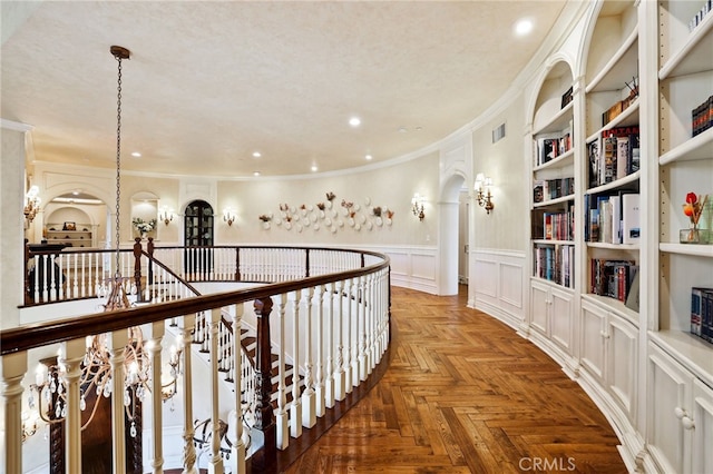 hall with a textured ceiling, parquet floors, and ornamental molding