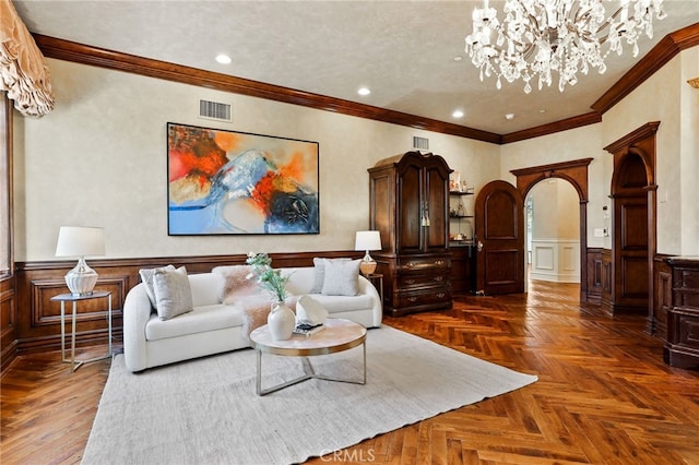 living room with dark parquet flooring, ornamental molding, and an inviting chandelier